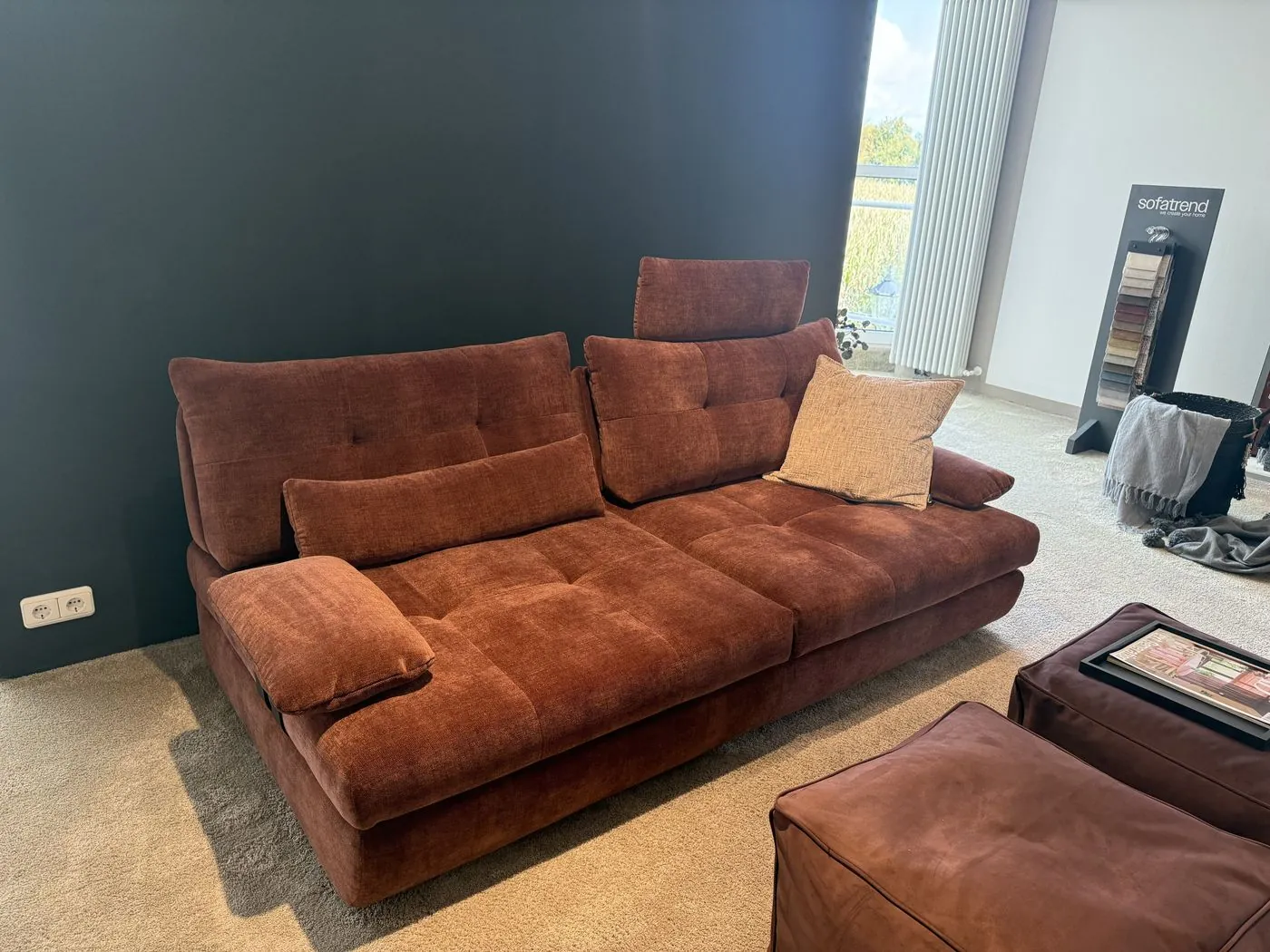 Sofa in rostrotem Samt vor dunkler Wand