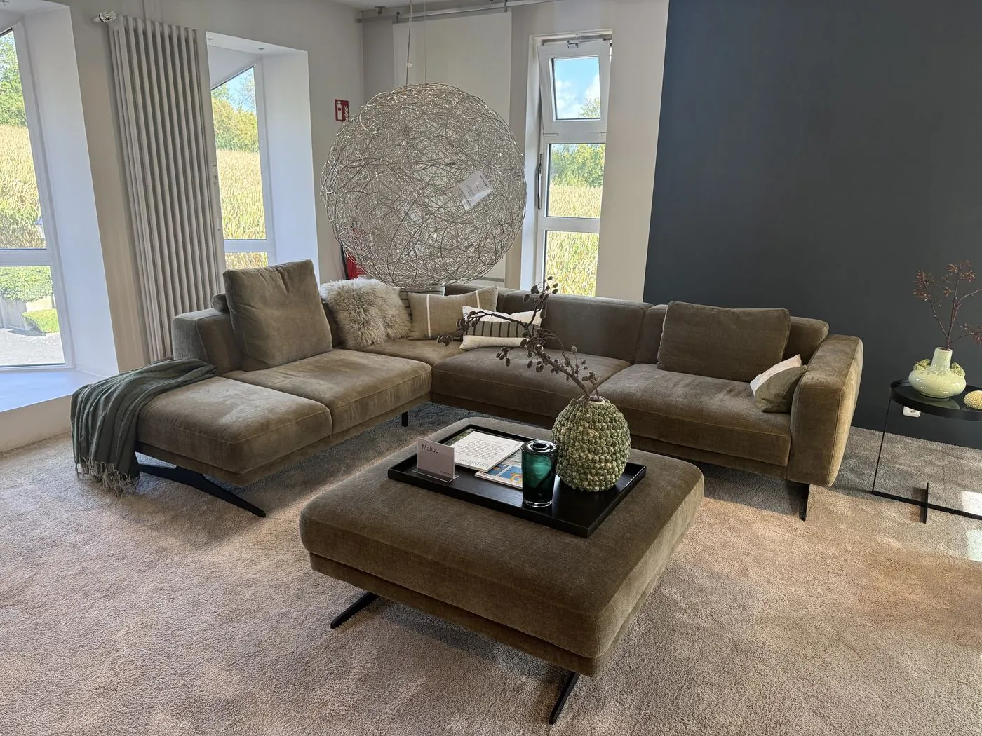 Ecksofa in Oliv mit Hocker unter der Kugelleuchte